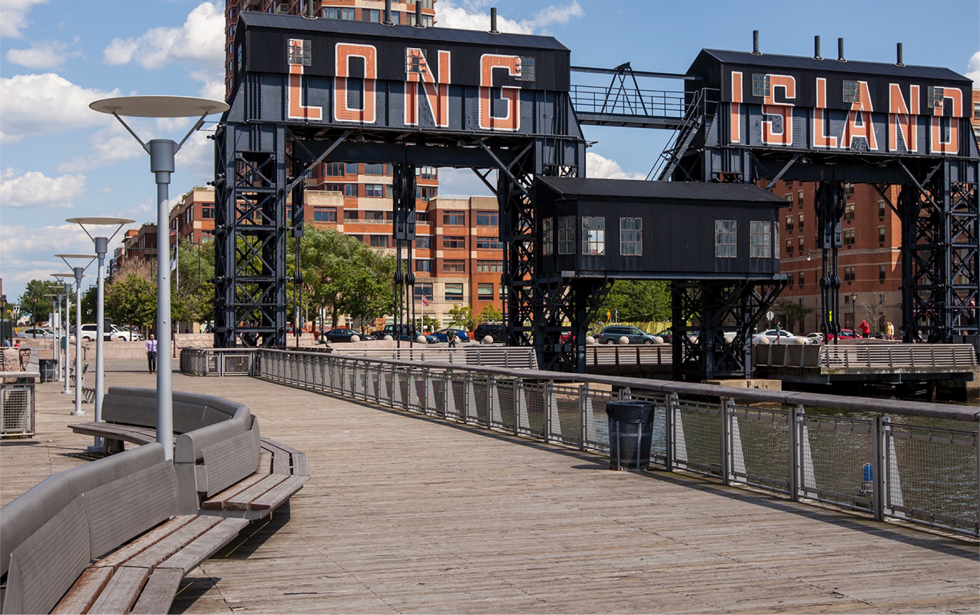 Black industrial building with 'Long Island' written in orange along a pedestrian walkway