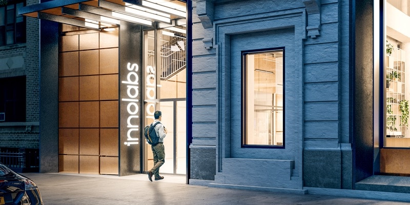 A man with a backpack walks into the Innolabs entrance at night